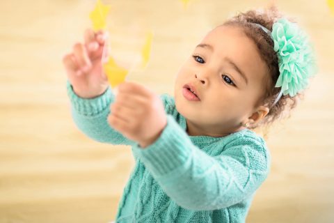 A child in teal holding up yellow paper