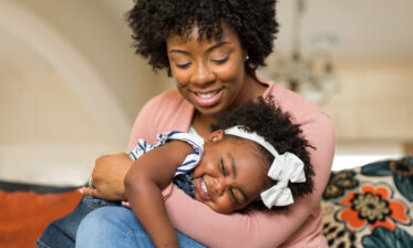 Black adoptive Mum holding her adopted daughter in her arms