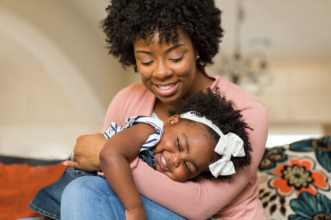 Black adoptive Mum holding her adopted daughter in her arms